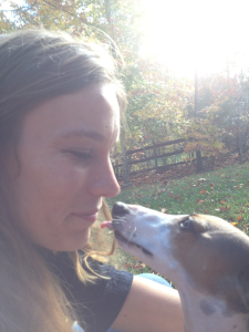 Dog trainer Ashleigh conducting a training session with a hound dog in a yard.