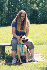 Dog trainer Ashleigh conducting a training session with a dog in a yard.
